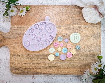 Pode incluir: Um molde de silicone com várias formas de botões e uma coleção de botões de argila polimérica feitos à mão em cores vibrantes.