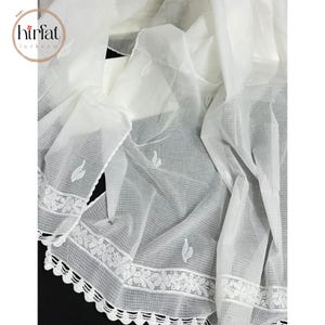 Puede incluir: Panel de cortina blanca de voile con un delicado ribete de encaje floral y dise&ntilde;os de hojas bordadas. La cortina est&aacute; hecha de una tela ligera y aireada.