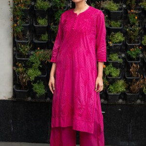May include: A magenta long-sleeved kurta with embroidered floral designs and matching palazzo pants. The kurta has a round neckline and a button closure.