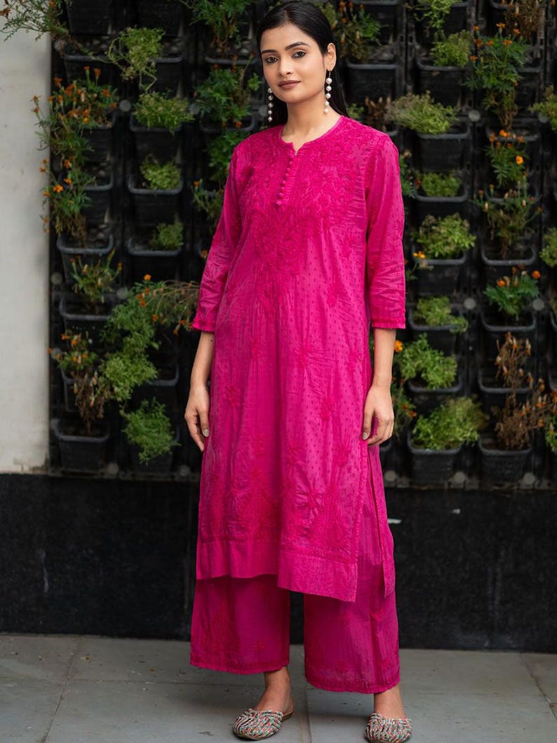 May include: A magenta long-sleeved kurta with embroidered floral designs and matching palazzo pants. The kurta has a round neckline and a button closure.
