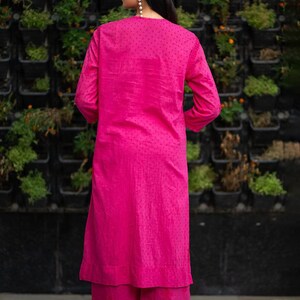 May include: A pink kurta and palazzo set with a dotted pattern. The kurta has long sleeves and a round neckline. The palazzo pants are wide-legged and flowy.