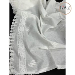 Puede incluir: Tela blanca transparente con un borde de ganchillo y dise&ntilde;os de hojas bordadas. La tela es ligera y tiene una textura delicada.