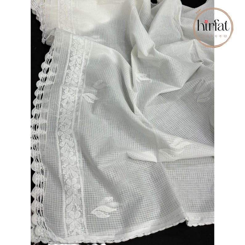 Puede incluir: Tela blanca transparente con un borde de ganchillo y dise&ntilde;os de hojas bordadas. La tela es ligera y tiene una textura delicada.