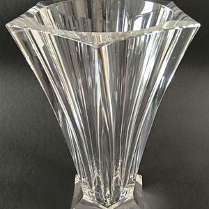 Könnte beinhalten: Eine klare Glasvase mit einem Sternmuster. Die Vase hat eine breite Öffnung und einen schmalen Boden. Sie ist aus Kristall gefertigt und hat eine polierte Oberfläche.