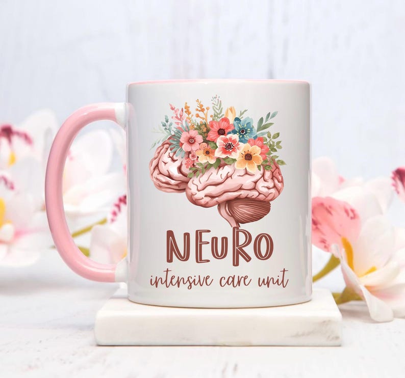 May include: White ceramic mug with a pink handle and interior. The mug features a brain illustration adorned with colorful flowers. The word "NEURO" is displayed in brown letters, with "intensive care unit" below.