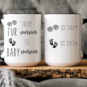May include: White ceramic mug with a black rim and handle. The mug has black text that reads "From Fur Mama to Baby Mama" with paw prints and footprints. The other side of the mug has black text that reads "Est. 2019" and "Est. 2024" with paw prints and footprints.