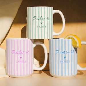 May include: Three ceramic mugs with vertical stripes in sage green, light pink, and light blue. Each mug features the text Chapter 60, a small heart icon, and the name AMANDA printed in a matching color. One mug contains a tea bag and another a lemon slice.