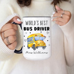 May include: White ceramic mug with a black rim and handle. The mug features a yellow school bus with the text "World's Best Bus Driver" and "Mrs. Williams".