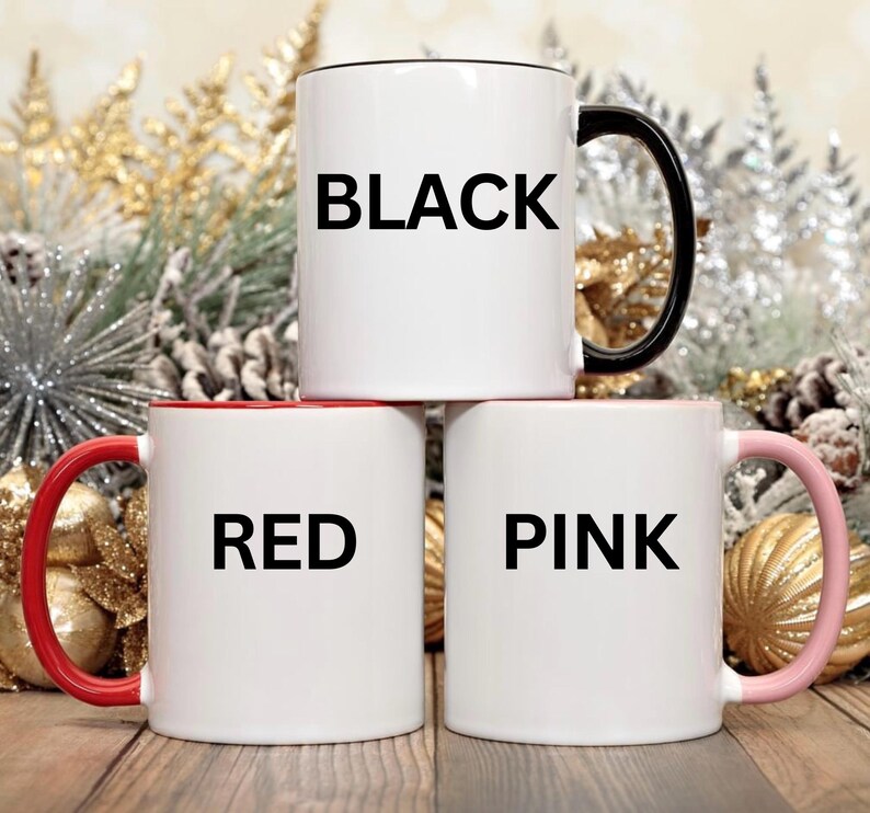 May include: Three white ceramic mugs with colored accents. The top mug has a black handle and the word "BLACK". The middle mug has a red handle and the word "RED". The bottom mug has a pink handle and the word "PINK".