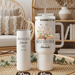 May include: Two white insulated tumblers with straws. One is a 20oz tumbler with the text "Walking with Jehovah Since 10.12.2025". The other is a 40oz tumbler with the text "Best Life Ever Amanda" and a floral design with butterflies. Both tumblers are on a woven surface.