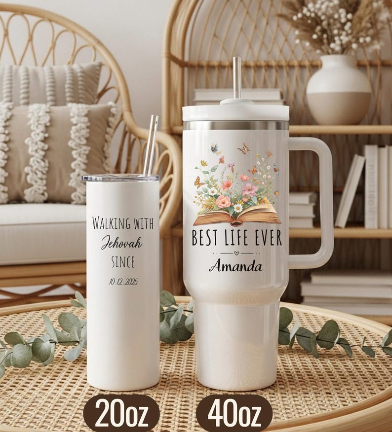 May include: Two white insulated tumblers with straws. One is a 20oz tumbler with the text "Walking with Jehovah Since 10.12.2025". The other is a 40oz tumbler with the text "Best Life Ever Amanda" and a floral design with butterflies. Both tumblers are on a woven surface.