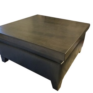 May include: A dark brown wooden coffee table with a black leather top and four legs. The table has a storage compartment.