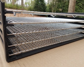 May include: A black food dehydrator with five chrome-plated wire mesh trays. The trays are stacked inside the dehydrator, which is made of black plastic.