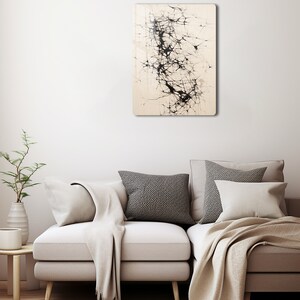 Puede incluir: Impresi&oacute;n de arte abstracto con l&iacute;neas y formas negras sobre un fondo crema. La impresi&oacute;n est&aacute; enmarcada y colgada en una pared blanca sobre un sof&aacute; beige claro.