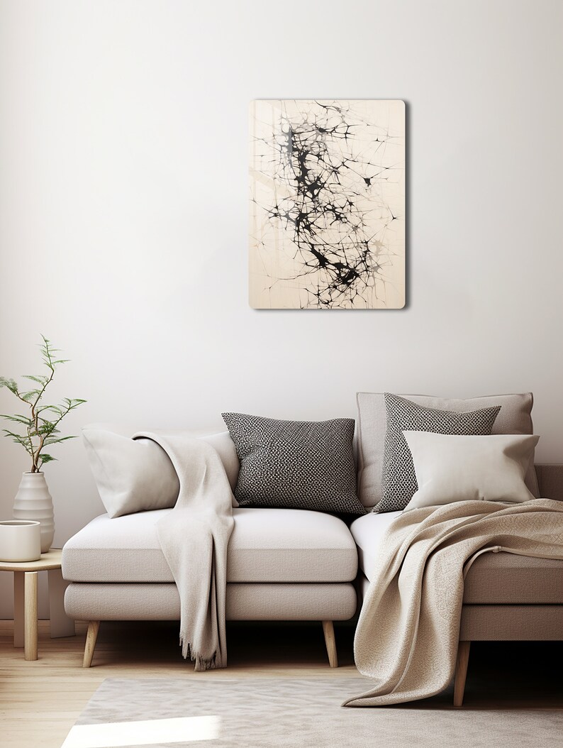 Puede incluir: Impresi&oacute;n de arte abstracto con l&iacute;neas y formas negras sobre un fondo crema. La impresi&oacute;n est&aacute; enmarcada y colgada en una pared blanca sobre un sof&aacute; beige claro.