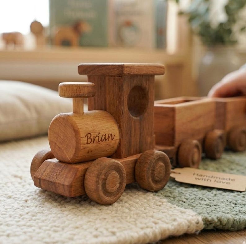 May include: A wooden toy train with the name "Brian" engraved on the side. The train is made of natural wood and has a classic design. The train has a small tag that says "Handmade with love".