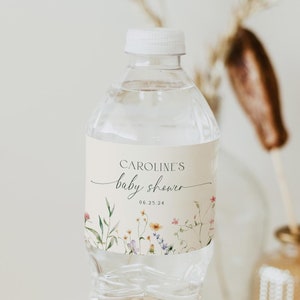 May include: A clear plastic water bottle with a white cap and a label that says "CAROLINE'S baby shower 06.25.24". The label features a floral design with pink, yellow, and purple flowers.