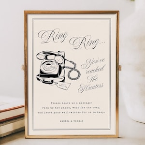 Könnte beinhalten: Ein gerahmtes Schild mit goldenem Rand zeigt eine Vintage-Telefon-Illustration in Schwarz. Der Text lautet "Ring Ring... You've reached The Hunters." Darunter steht "Please leave us a message!" und die Namen "AMELIA & THOMAS".