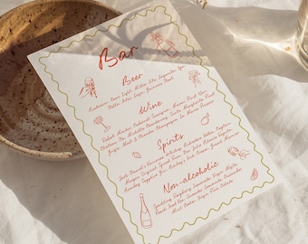 May include: A white paper menu with a green border and red text lists the bar's drink options, including beer, wine, spirits, and non-alcoholic beverages. The menu is on a white linen tablecloth with a small brown bowl and a glass of water in the background.