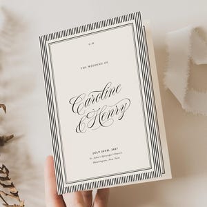 May include: A cream-coloured wedding programme card featuring black text and a double-line border. The text reads: C.H, THE WEDDING OF, Caroline & Henry, JULY 28TH, 2017, St. John's Episcopal Church, Huntington, New York. The card has a vertical orientation.