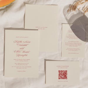 May include: A wedding invitation suite featuring cream-coloured cards with burgundy text. The suite includes an invitation, RSVP card with a QR code, and details card. A slice of papaya is in the upper left corner.