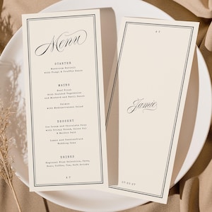 Könnte beinhalten: Zwei cremefarbene Hochzeitsmenükarten mit schwarzem Text und schwarzem Rand, auf einem weißen Teller präsentiert. Auf einer Karte steht "Menu" in eleganter Schrift. Auf der anderen Karte steht "Jamie" in Schrift. Eine getrocknete Pflanze und beiger Stoff sind im Hintergrund.
