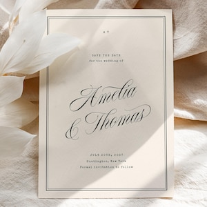 Puede incluir: Una invitación de boda color crema con texto negro, con los nombres "Amelia & Thomas" en escritura elegante. La invitación incluye la fecha, el lugar y una nota sobre una invitación formal a seguir. Un elemento floral blanco está en el fondo.