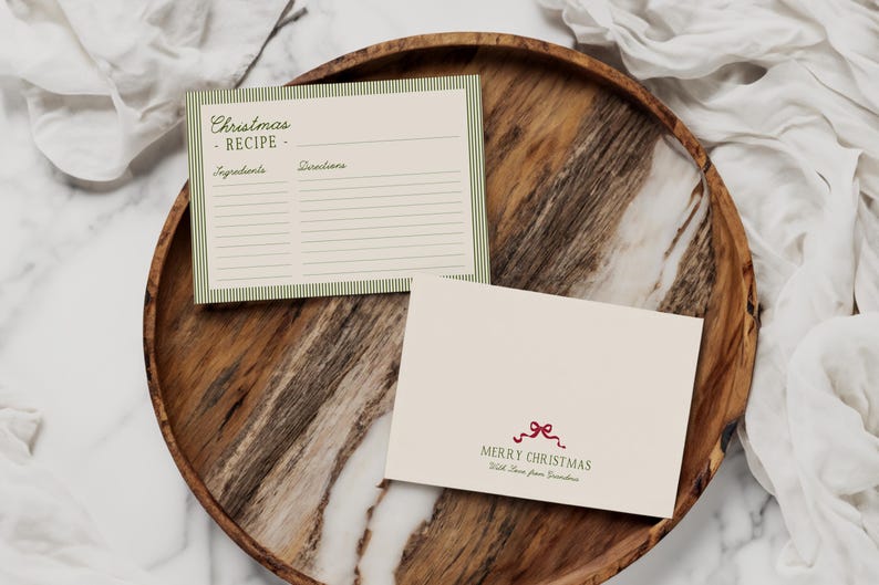 May include: A wooden serving tray holds a Christmas recipe card and a greeting card. The recipe card has a green striped border and the words "Christmas Recipe." The greeting card says "Merry Christmas" with a red bow.