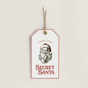 May include: White gift tag with a red border and a drawing of Santa Claus with his finger to his lips. The text "From your Secret Santa" is printed in red.