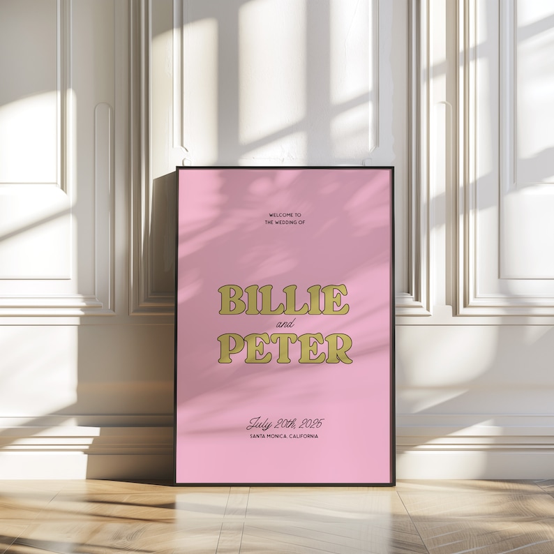 K&ouml;nnte beinhalten: Rosa Hochzeitseinladung mit goldener Schrift. Es steht "Willkommen zur Hochzeit von Billie und Peter. 20. Juli 2025. Santa Monica, Kalifornien."