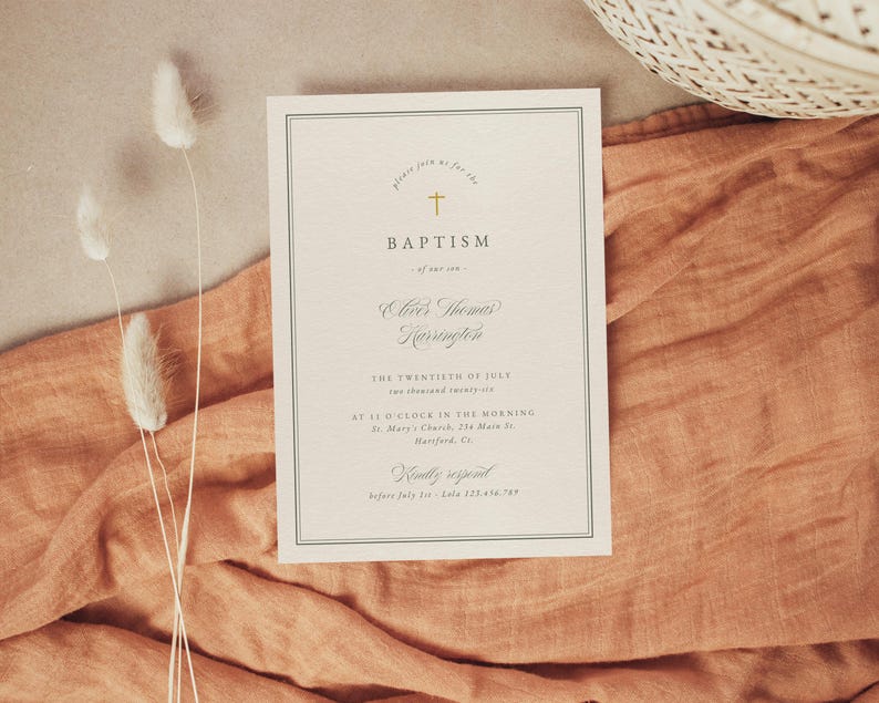 May include: A cream-colored baptism invitation with a gold cross and elegant script. The invitation includes the word "BAPTISM" and other details. The card is set on a peach-colored fabric with dried flowers.