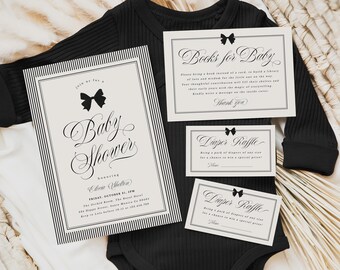 Könnte beinhalten: Ein schwarzer Baby-Body mit Babyparty-Einladungen und Loskarten. Die Einladungen und Karten sind cremefarben mit schwarzem Text und Schleifenakzenten. Auf der Haupteinladung steht "Baby Shower" in eleganter Schrift.