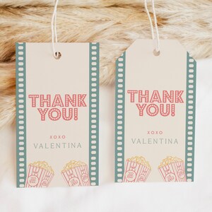 Peut inclure: Deux &eacute;tiquettes de remerciement avec une bordure de pellicule de film. Les &eacute;tiquettes sont de couleur cr&egrave;me avec du pop-corn rouge et blanc et le texte "Merci !" en rouge avec des pois blancs. Le texte "XOXO Valentina" est en noir.