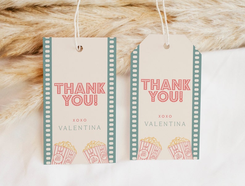 Peut inclure: Deux &eacute;tiquettes de remerciement avec une bordure de pellicule de film. Les &eacute;tiquettes sont de couleur cr&egrave;me avec du pop-corn rouge et blanc et le texte "Merci !" en rouge avec des pois blancs. Le texte "XOXO Valentina" est en noir.