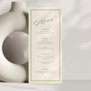 May include: A rectangular menu card with a green border and elegant script font. The word "Menu" is at the top, with a list of courses below. The background is a soft beige colour.