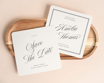 May include: Two square white cards with rounded corners featuring black text. One card reads Save The Date, Amelia & Thomas, and Formal invitation to follow. The other card reads Save The Date for the wedding of Amelia & Thomas, July 20th, 2027.