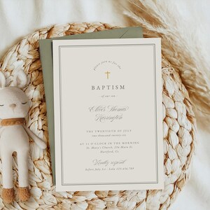 May include: A baptism invitation with a gold cross and elegant font, placed on a woven placemat with a stuffed bunny. The invitation includes the text "Baptism" and event details. A sage green envelope is behind the invitation.