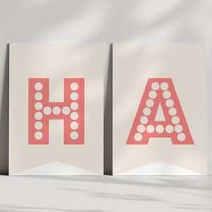 Peut inclure: Deux banni&egrave;res de couleur cr&egrave;me avec les lettres "HA" en grandes lettres rouges soulign&eacute;es. Les lettres sont compos&eacute;es de cercles blancs.