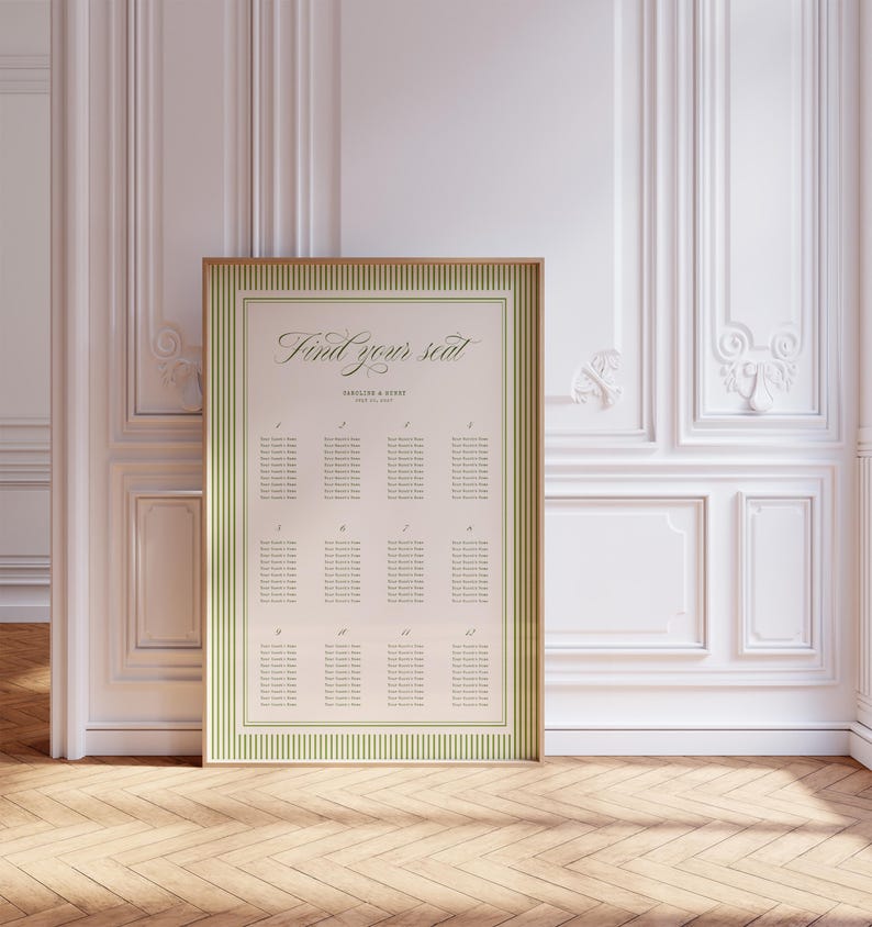 May include: A framed seating chart with the text "Find your seat" in elegant script. The chart has a cream background with green striped borders and a gold frame. The background is a white wall with decorative molding.