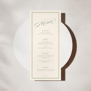 May include: A cream-coloured menu card with a green border, featuring the word "Menu" in cursive. The menu lists starters, mains, desserts, and drinks. The card is placed on a white circular surface. The background is a neutral tone.