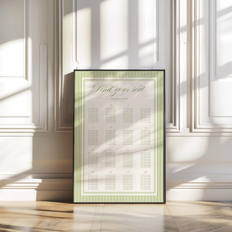 May include: A framed seating chart with the text "Find your seat" in elegant script. The chart has a cream-colored background with a green striped border and a black frame. The chart is leaning against a white wall.