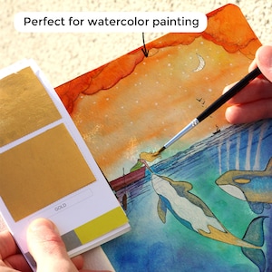 Peut inclure: Une peinture &agrave; l'aquarelle d'une fille dans un bateau avec deux orques. Le ciel est orange et l'eau est bleue. La peinture est d&eacute;cor&eacute;e de feuilles d'or.