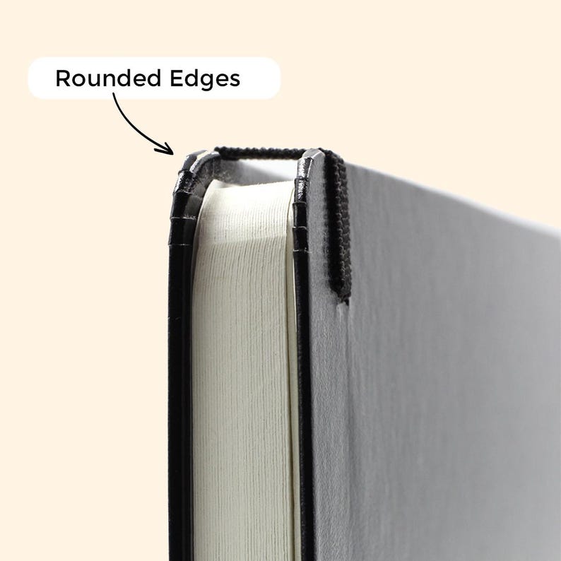 Peut inclure: Gros plan sur un carnet noir aux bords arrondis. Le carnet a une couverture noire et des pages blanches.