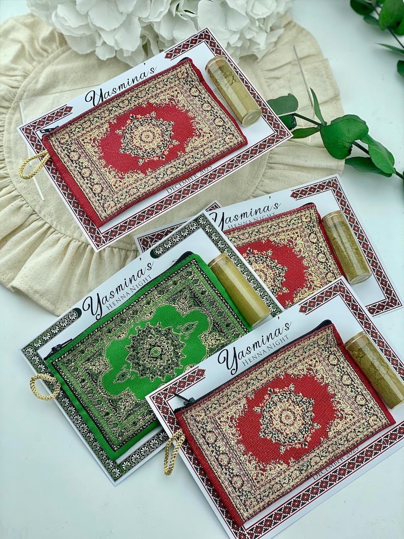 Five favor sets are arranged on a white surface, with mini wallets in red, green, and beige patterns, each with a henna tube and a personalized card.