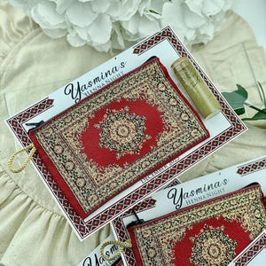 Four red patterned mini wallet favor sets are displayed, each with a henna tube and a personalized card.