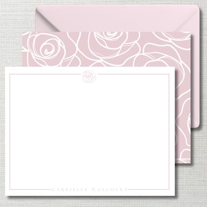 May include: A set of stationery featuring a light pink rose design. The set includes a blank card with a rose outline, a matching envelope, and a rose pattern on the back of the card. The name "GABRIELLE RANCOURT" is printed at the bottom of the card.