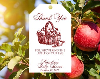 May include: A white tag with a burgundy illustration of a basket filled with apples. The tag reads "Thank You" and "For Showering the Apple of Our Eye." Below is "Karoline's Baby Shower" and the date "October 18, 2025."