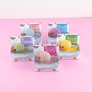 Op de afbeelding: Vier kleine gehaakte eendjes in verschillende kleuren, elk in een witte badkuipdoos met een andere boodschap op de voorkant. De boodschappen zijn: "You make me feel so ducky!" "In a world full of pigeons be a fabulous DUCK!" "I ducking Love you!" en "If life gives you lemons be a DUCK!"