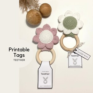 Op de afbeelding: Twee gehaakte bloembeetringen met houten ringen. De bloemen zijn roze en wit, en groen en wit. De labels zeggen "Je nieuwe beetring 100% handgemaakt" en "Gehaakt door mij beetring 100% handgemaakt".