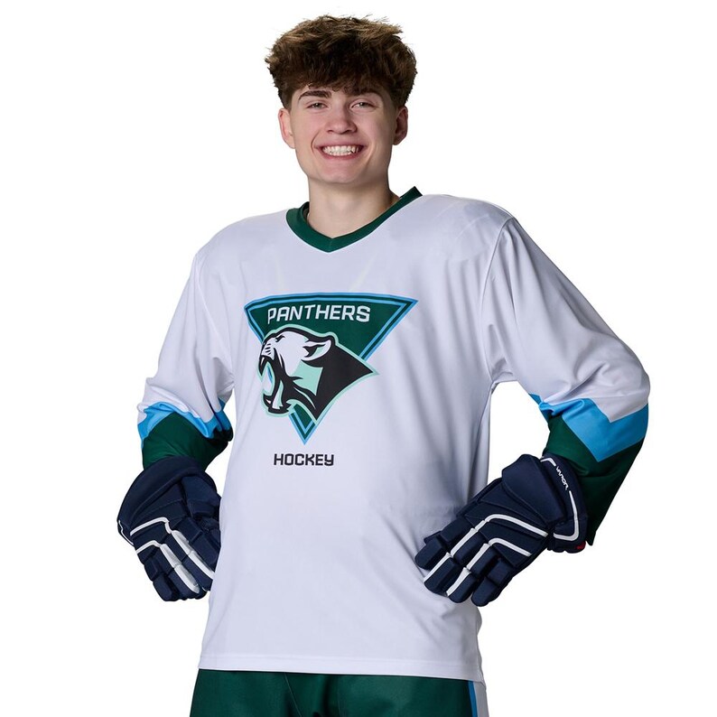 May include: A white hockey jersey with a V-neck collar, featuring a teal and dark green triangular emblem on the chest with a black panther graphic and the text PANTHERS HOCKEY. The sleeves have teal and dark green bands, paired with navy blue gloves.